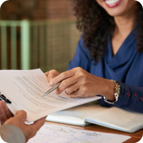 A businessperson hands paperwork to a client. 